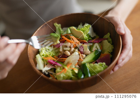 サラダを食べる若い女性の手元 111295076