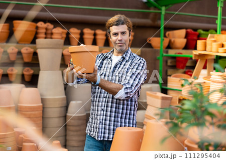 Portrait of man choosing pots for flowers and trees in gardening market Portrait of man choosing pots for flowers and trees in gardening market 111295404