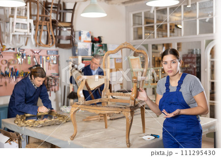 Female positive restorer restores the wooden frame of an antique chair Female positive restorer restores the wooden frame of an antique chair 111295430