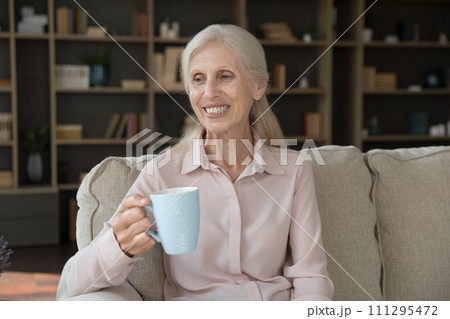 Middle-aged woman relax on sofa with cup of tea 111295472