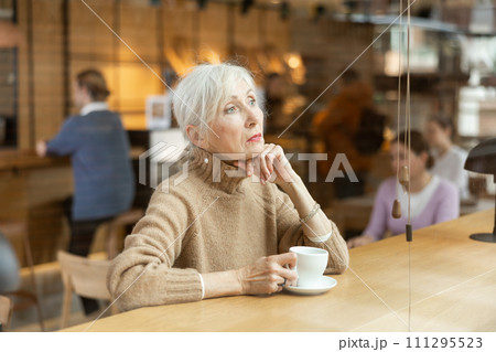 Calm mature woman enjoying peace and quiet alone in cozy cafe 111295523