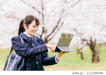 桜の中でタブレットPCを使う中学生・高校生・女子高生・女子高校生 111296096