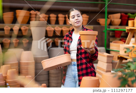 Portrait of woman choosing pots for flowers in gardening market Portrait of woman choosing pots for flowers in gardening market 111297177