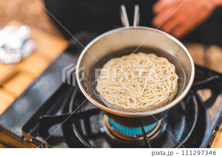 キャンプ飯でインスタントラーメン・袋麺を食べるキャンパーの男性 キャンプ飯でインスタントラーメン・袋麺を食べるキャンパーの男性 111297346