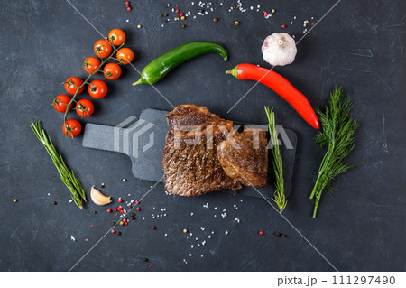 Grilled beef steak ribeye rare on on dark background top view Grilled beef steak ribeye rare on on dark background top view 111297490