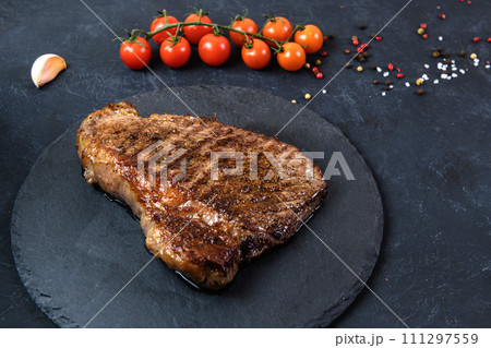 Grilled beef steak ribeye rare on on dark background Grilled beef steak ribeye rare on on dark background 111297559