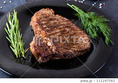 Grilled beef steak ribeye rare on on dark background Grilled beef steak ribeye rare on on dark background 111297561