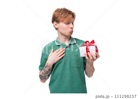 young red-haired caucasian guy in a green t-shirt is going to received a gift for his holiday 111298237