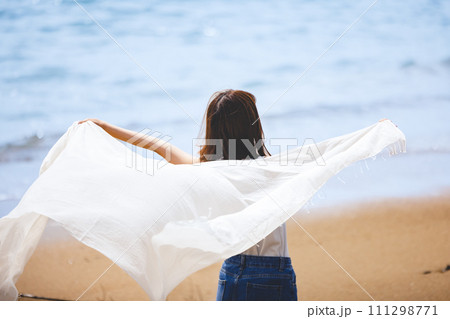 砂浜で白い布を持って立つ女性 111298771