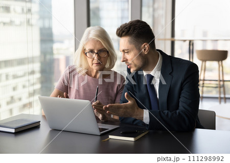 Focused younger and older business colleagues discussing collaboration Focused younger and older business colleagues discussing collaboration 111298992
