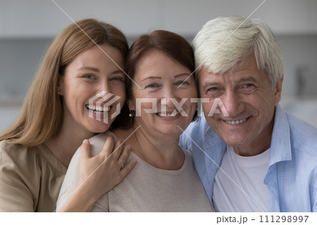 Positive old senior woman hugging mature husband and adult daughter 111298997