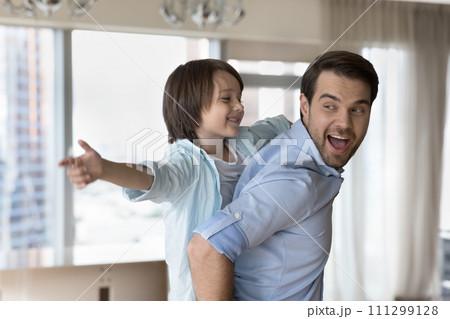 Happy man playing with cute little son at home 111299128