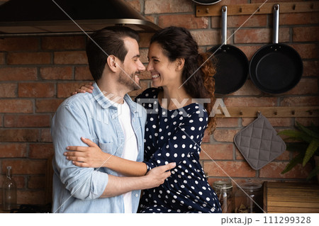 Happy loving millennial couple hugging, enjoying romantic moment in kitchen 111299328