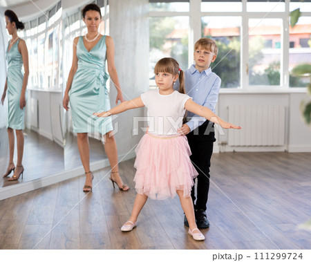 Tween girl and boy practicing waltz in dance hall with female mentor Tween girl and boy practicing waltz in dance hall with female mentor 111299724