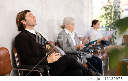 Portrait of serious man waiting for job interview while sitting at office lobby Portrait of serious man waiting for job interview while sitting at office lobby 111299774