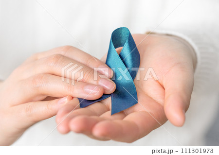 Holding blue ribbon for cancer awareness month. Healthcare and world cancer day concept. Holding blue ribbon for cancer awareness month. Healthcare and world cancer day concept. 111301978