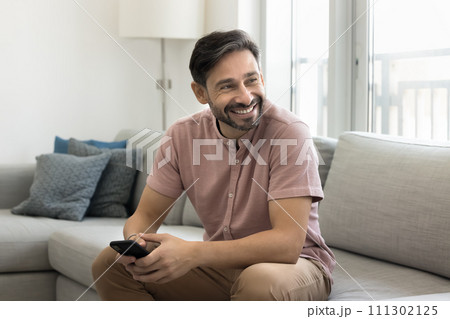Cheerful middle aged man using mobile phone at home Cheerful middle aged man using mobile phone at home 111302125