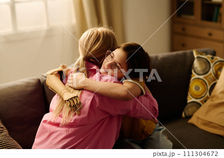 Mother and daughter sitting in embrace Mother and daughter sitting in embrace 111304672