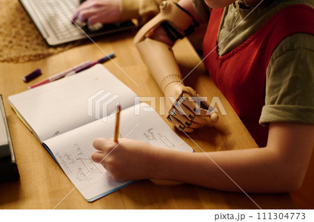 Girl with partial arm doing homework 111304773