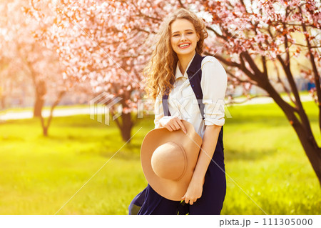 Outdoor portrait of young beautiful fashionable lady posing near flowering tree. 111305000
