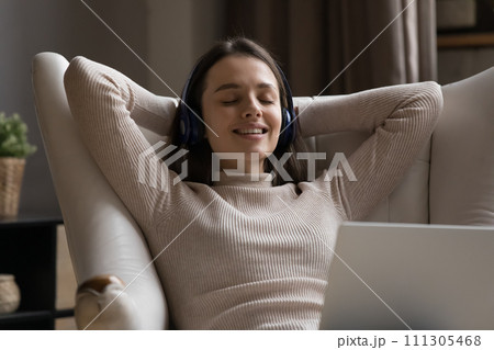 Woman listen music while relaxing on armchair with laptop 111305468