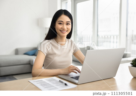 Happy beautiful Asian student girl studying at laptop at home 111305501