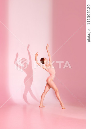Whispering Grace. Ballerina in pink attire dancing against soft background, her shadow mimicking her every move. Whispering Grace. Ballerina in pink attire dancing against soft background, her shadow mimicking her every move. 111306120