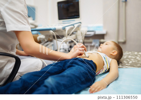 Boy undergoing thyroid ultrasound examination. Doctor examining kid throat in clinic with equipment. 111306550