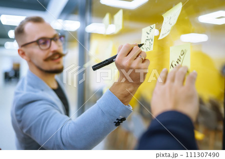 Young business people discussing and planning strategy Front of glass wall marker and stickers. Young business people discussing and planning strategy Front of glass wall marker and stickers. 111307490