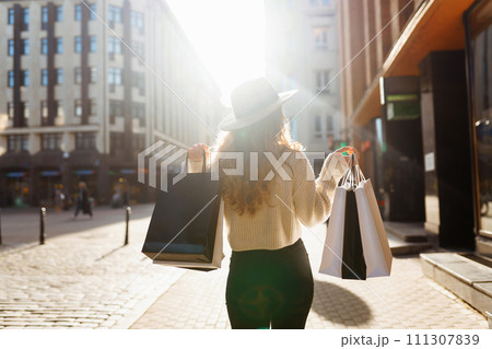Stylish woman after shopping on city street. Purchases, black friday, discounts, sale concept. 111307839
