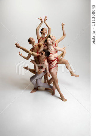 Group of ballet dancers, tied together with red strings, creating intricate pose against white studio background. Balance and harmony Group of ballet dancers, tied together with red strings, creating intricate pose against white studio background. Balance and harmony 111308048