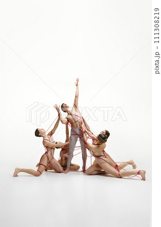 Reach out of comfort zone. Ballet dicers connected with red strings performing against white studio background. Social manipulation Reach out of comfort zone. Ballet dicers connected with red strings performing against white studio background. Social manipulation 111308219