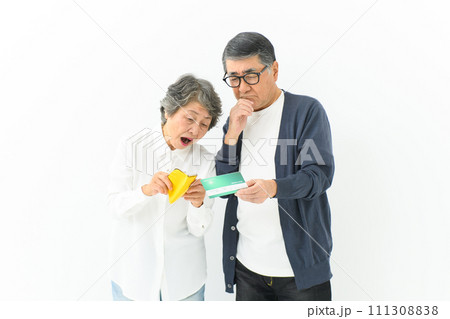 通帳と財布を持って悩むシニア夫婦 通帳と財布を持って悩むシニア夫婦 111308838