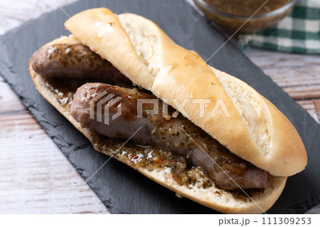 Traditional choripan, Argentina sandwich with chorizo and chimichurri sauce on wooden table Traditional choripan, Argentina sandwich with chorizo and chimichurri sauce on wooden table 111309253