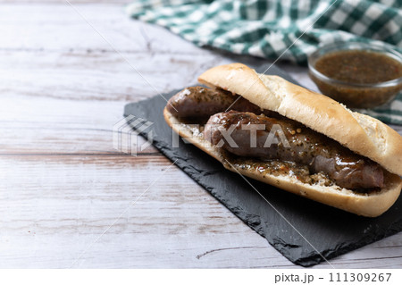 Traditional choripan, Argentina sandwich with chorizo and chimichurri sauce on wooden table Traditional choripan, Argentina sandwich with chorizo and chimichurri sauce on wooden table 111309267