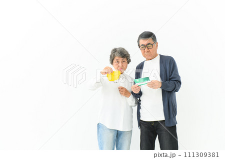 通帳と財布を持って悩むシニア夫婦 111309381