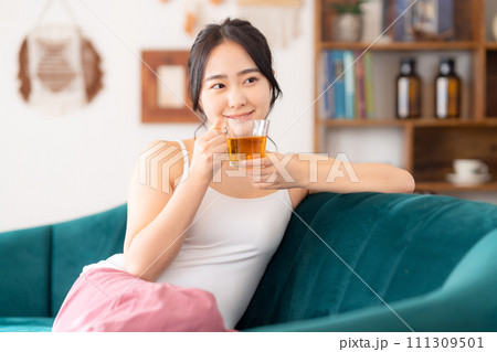 部屋でお茶を飲む大学生の女性 部屋でお茶を飲む大学生の女性 111309501