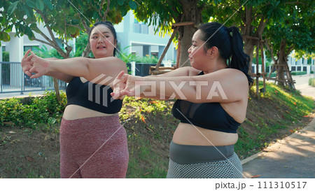 Obese two young asian woman doing stretching arm muscle in the park. Obese two young asian woman doing stretching arm muscle in the park. 111310517