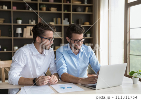 Two male twins business partners sit at desk using laptop 111311754