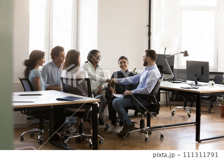 Happy multiethnic male business coworkers shaking hands on team meeting 111311791