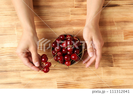 Ripe cherry fruits in a bowl on a wooden background 111312041