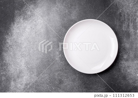 Empty round ceramic plate on a light texture background Empty round ceramic plate on a light texture background 111312653
