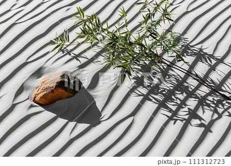 Bamboo leaves and rocks on white sand dune with shadow. Bamboo leaves and rocks on white sand dune with shadow. 111312723