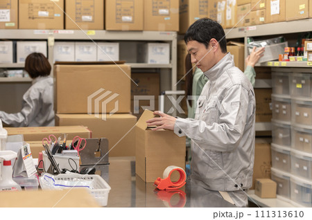 梱包作業する作業服姿の男女 111313610