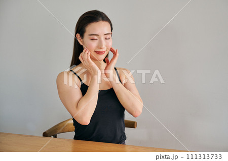 顔をマッサージして肌のお手入れをする30代女性 顔をマッサージして肌のお手入れをする30代女性 111313733