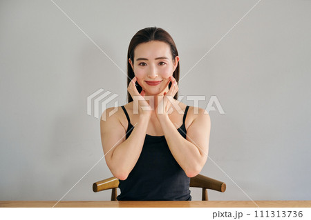顔をマッサージして肌のお手入れをする30代女性 111313736