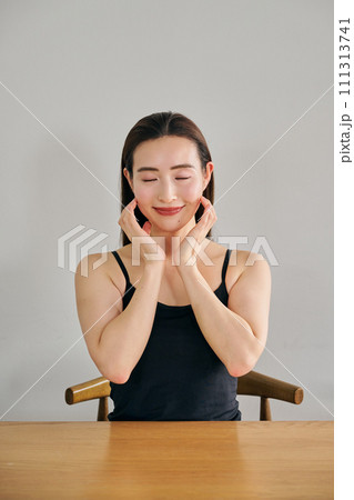 顔をマッサージして肌のお手入れをする30代女性 111313741