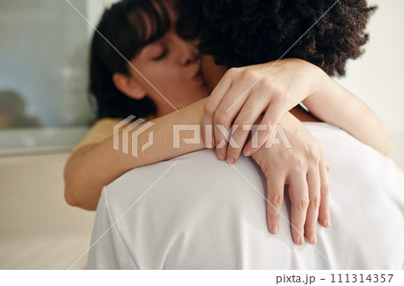 Hands of young affectionate woman with closed eyes embracing her husband by neck and kissing him in front of camera 111314357