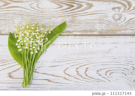 Happy May Day greeting card concept; Bouquet of lilies-of-the valley on a white wooden background; copy space 111317143