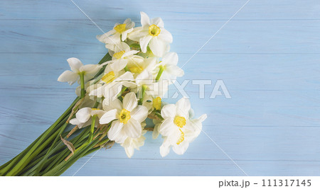 Bouquet of white daffodils on a blue paint wooden background; copy space 111317145
